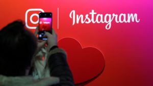 A visitor takes a picture of the Instagram application logo at the Young Entrepreneurs fair in Paris